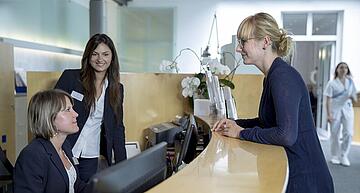Artemed Fachklinik München Empfangsthresen Empfangsdamen unterhalten sich mit Patientin